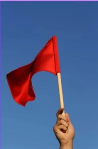 A hand holding a red flag, warning business owners about the importance of knowing how to hire SEO outsourcing services and what questions to ask to avoid mistakes.