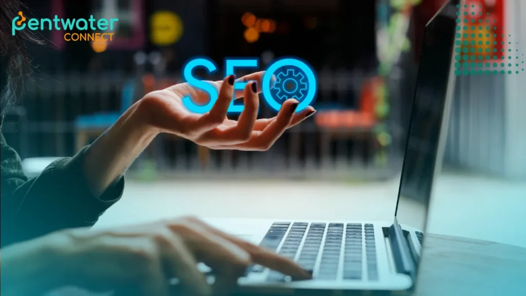 A person's hands are positioned over a laptop keyboard, with one hand holding a glowing, holographic "SEO" icon above it.