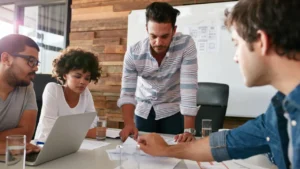 A group discussing business strategies around a table "What Is the Best SEO Outsourcing Solution? Learn to identify the ideal SEO company for your business needs in 2025.